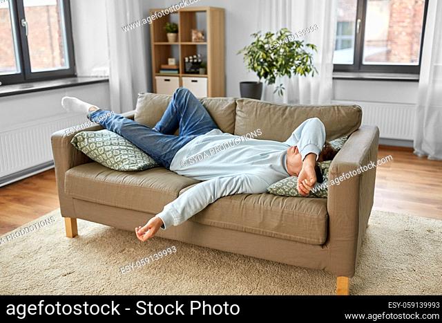 bored or lazy young man lying on sofa at home