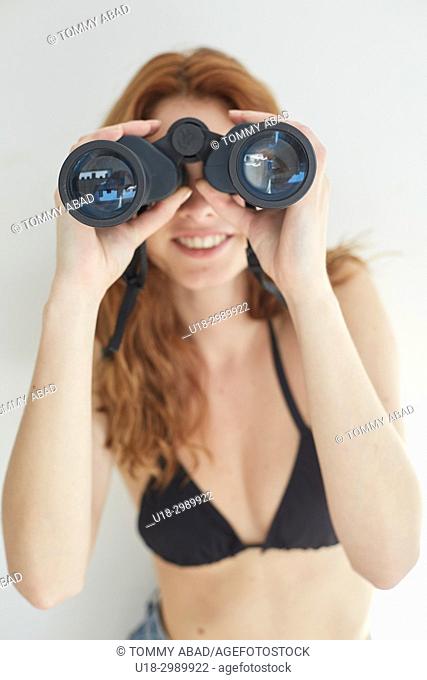Young redhead woman using binoculars