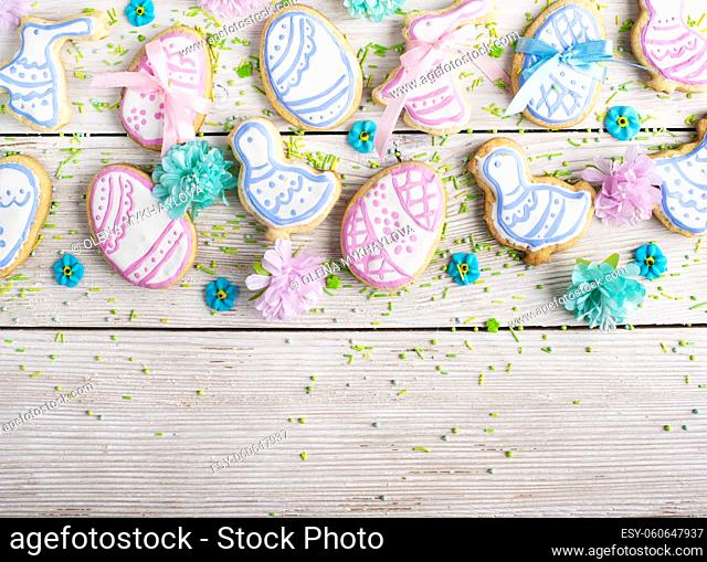 Homemade Easter cookies in shape of eggs chicken and rabbit on white wooden kitchen table flat lay view. Space for text