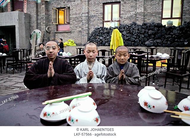 Young monks eating lunch, coal used cooking in the background, during birthday celebrations for Wenshu, Mount Wutai, Wutai Shan, Five Terrace Mountain