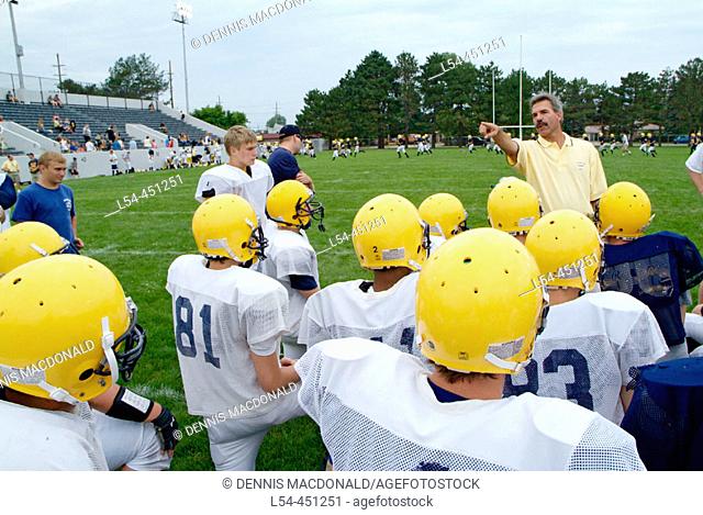 High school football coach give pep talk to players prior to practice session