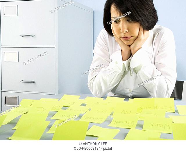 Confused businesswoman looking at adhesive notes