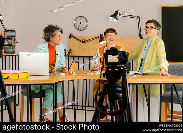 Three women sitting in studio and recording video on the camera
