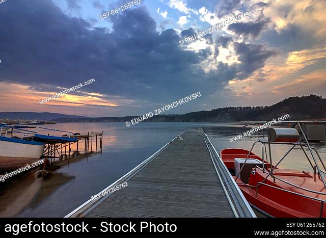 the exciting landscape of wooden pier and boats at sunset