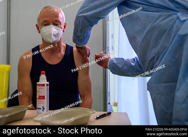 26 February 2021, Saxony-Anhalt, Burg: A doctor vaccinates the sports teacher Jürgen Dittrich against the corona virus with the active ingredient from Astra...