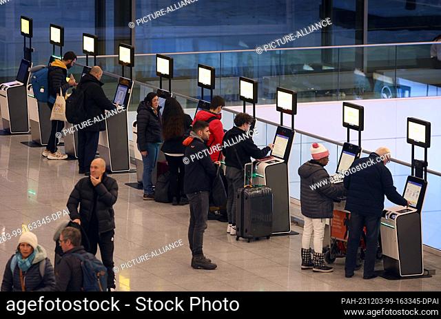 03 December 2023, Bavaria, Munich: Passengers stand at check-in at Munich Airport. Munich Airport resumed flight operations at 06:00 on Sunday