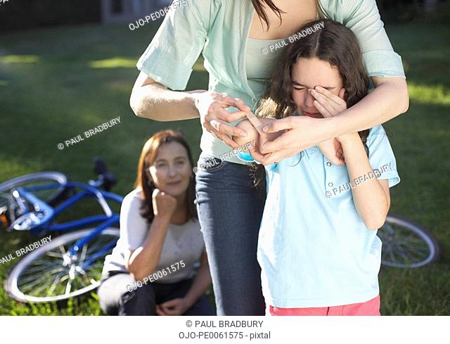 Two women helping an injured young girl who fell off her bike