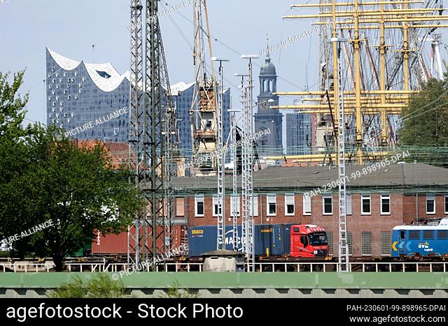 10 May 2023, Hamburg: View through the harbor with cranes and ship masts to the Elbphilharmonie and the city landmark, the main church of St
