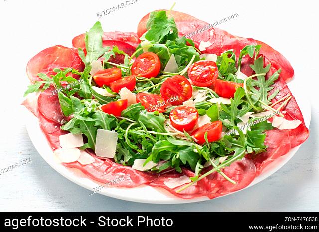 Plate of bresaola with rocket parmesan and cherry tomatoes