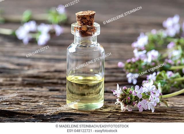 A bottle of essential oil with fresh blooming thyme twigs