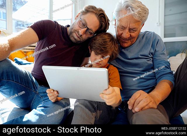 Multi-generation family watching movie on tablet PC at home