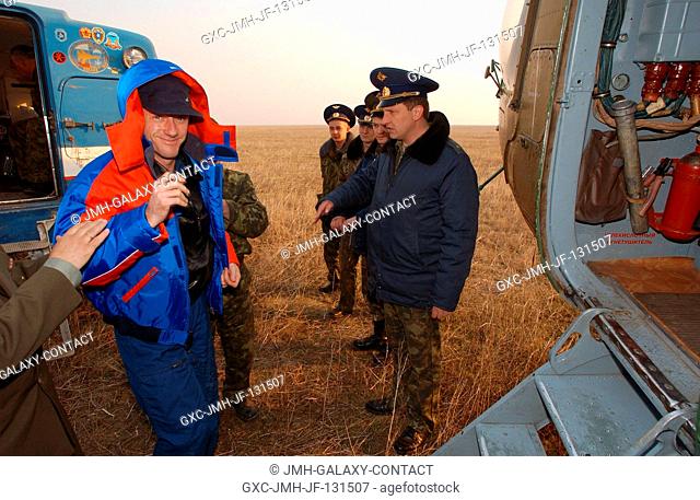 Astronaut C. Michael Foale (left), Expedition 8 commander and NASA ISS science officer, exits the all terrain vehicle and prepares to enter a Russian MI-8...