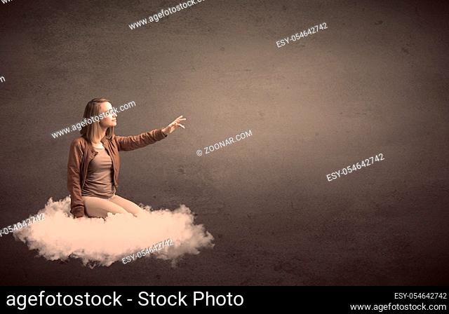 Caucasian woman sitting on a white fluffy cloud daydreaming beside a plain grunge background