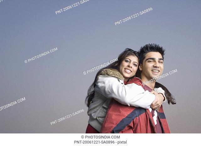 Side profile of a young woman riding piggyback on a young man