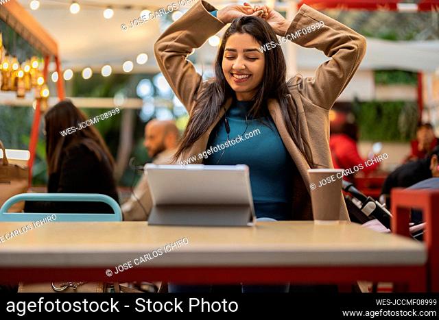 Smiling woman with eyes closed sitting in cafe