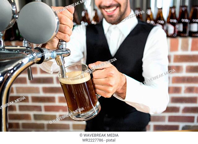 Handsome barman pouring beer