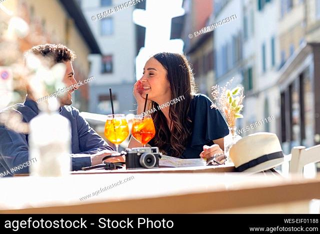 Couple with drinks talking while sitting at sidewalk cafe