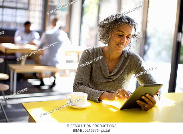 Older woman using digital tablet in cafe