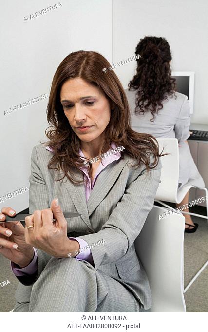 Businesswoman filing her nails at work