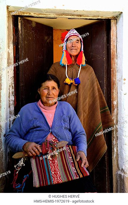 Peru, Cuzco province, Ccatcca, weavers couple in traditional dress in front of their workshop making alpaca wool tissues