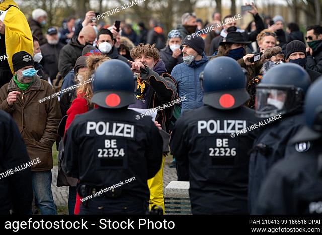 13 April 2021, Berlin: Police officers stand in front of demonstrators protesting against the tightening of the infection protection law in the government...
