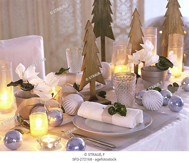 Christmas table with Cyclamen and wooden fir trees