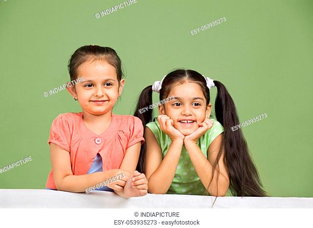 Cute little girls looking away over colored background