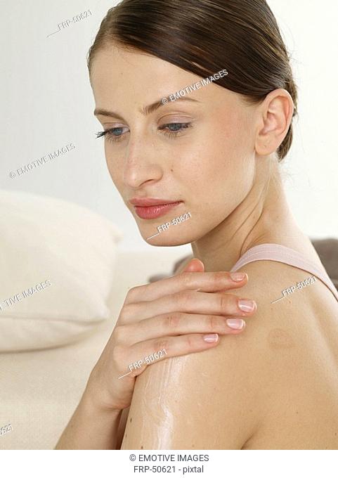 Woman creaming her shoulder