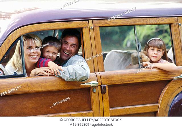 family in an old 'woody' station wagon car