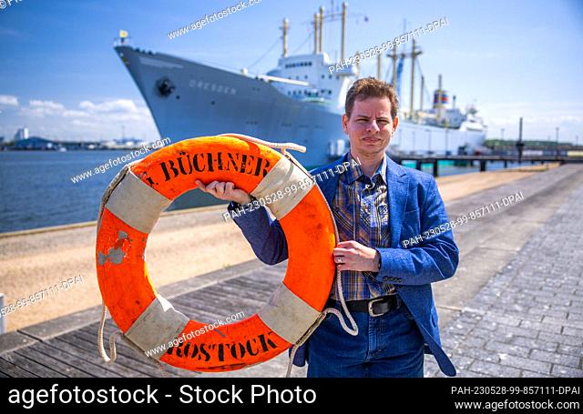 28 May 2023, Mecklenburg-Western Pomerania, Rostock: Filmmaker Merlin Franke holds an original life preserver of the cargo and passenger ship ""Georg Büchner""