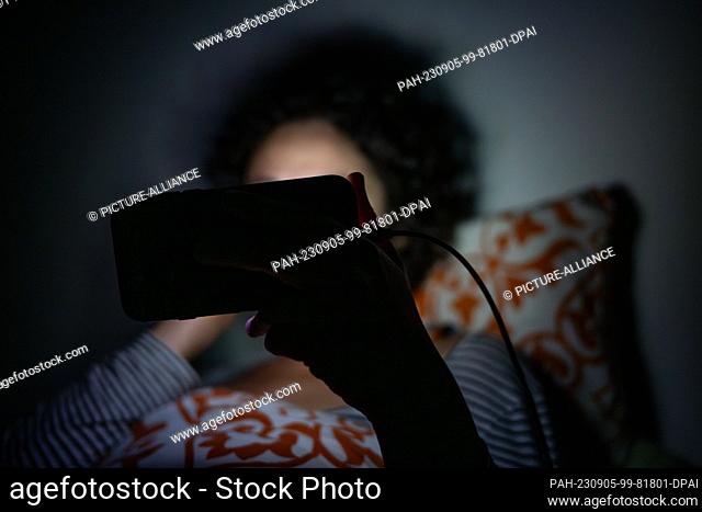 PRODUCTION - 01 September 2023, Berlin: A woman watches a program on a smartphone in a bed. On 05.09.2023, the ""Leisure Monitor 2023"" was presented in Hamburg