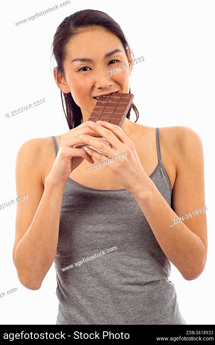 Happy Asian woman eating chocolate bar isolated over white background