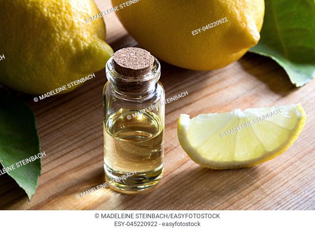 A bottle of lemon essential oil on a wooden table, with lemons in the background