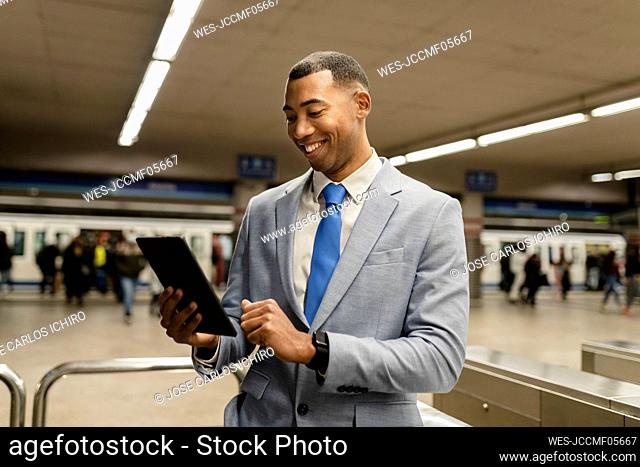 Happy businessman using tablet PC at train station