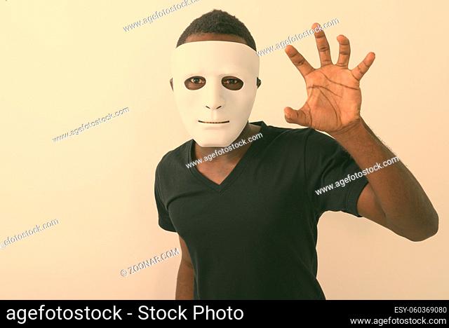 Studio shot of young African man with white mask against white background
