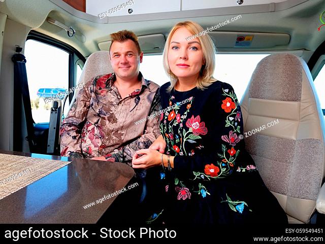 Married middle age couple sitting inside of recreational vehicle looking at camera. Active people lifestyle, adventure and journey