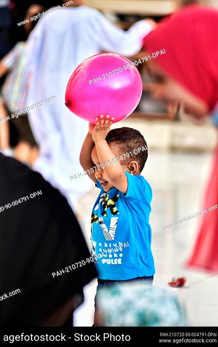 20 July 2021, Egypt, Cairo: A child plays with a balloon ahead of Eid al-Adha morning prayers at Al Azhar mosque. Eid al-Adha is the holiest feast in Islam