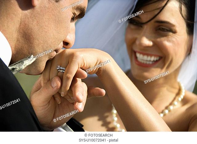 Caucasian Adult male groom kissing hand of female bride