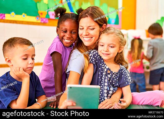 Tagesmutter und Kinder machen ein Selfie mit dem Tablet Computer im Kindergarten oder Hort