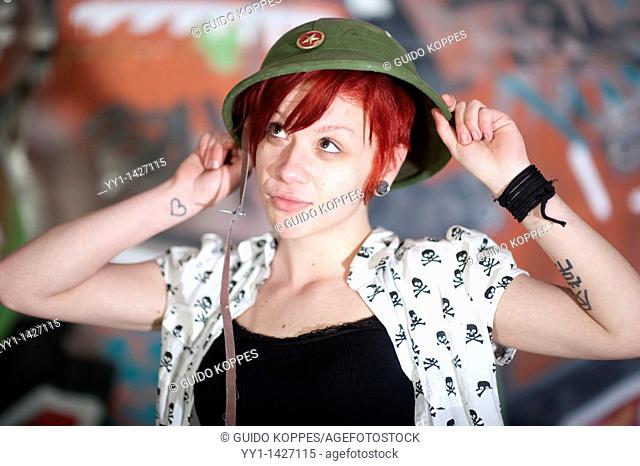Rotterdam, Netherlands. A young woman with cap posing in front of a graffiti, during a youth seventies party