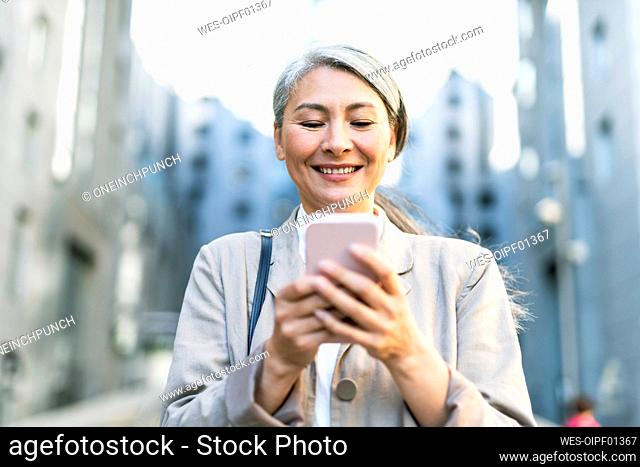 Smiling woman text messaging through smart phone