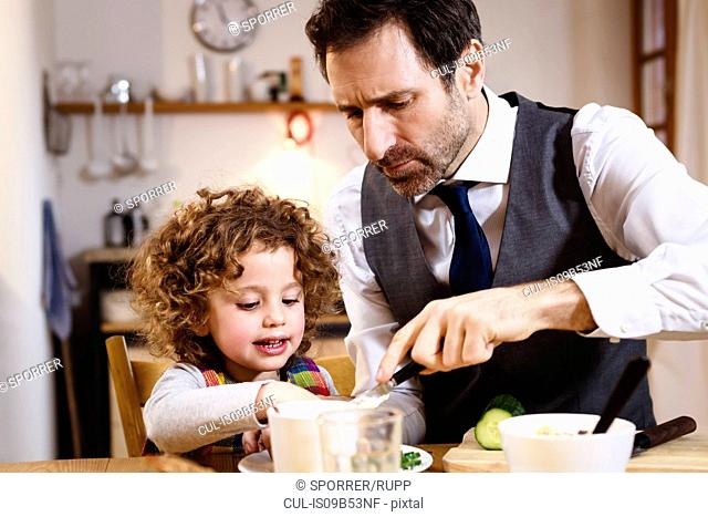 Man helping daughter with snack at table