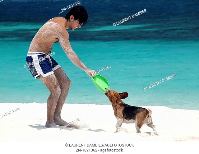 Young European man playing with his dog a sandy beach in Malaysia