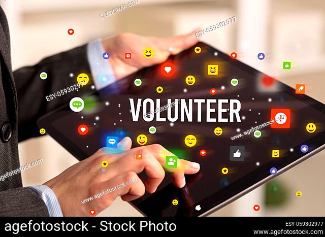 Close up of business person playing multimedia with social media icons and VOLUNTEER inscription