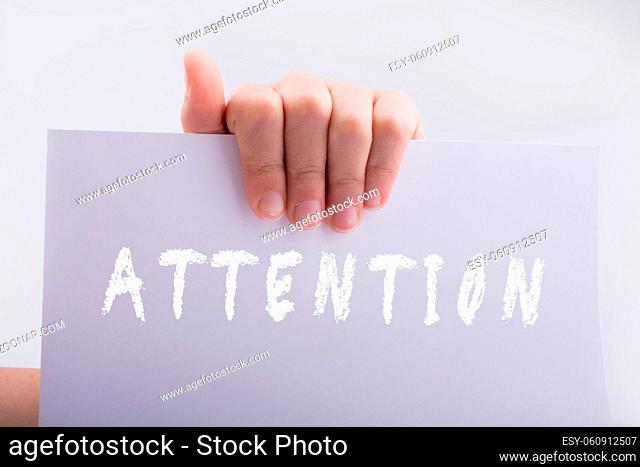 Hand holding a white paper with attention wording on white