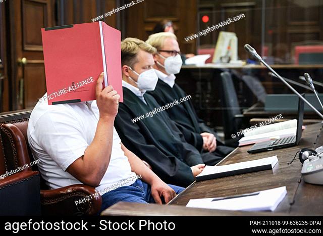 18 October 2021, Hamburg: The defendant (l) sits next to his lawyers Dennis Dördrechter (M) and Christian Denzel in the courtroom at the Criminal Justice...