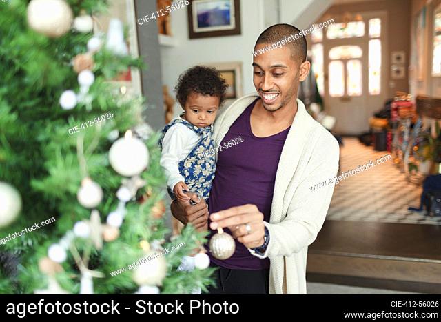 Happy father and baby daughter decorating Christmas tree