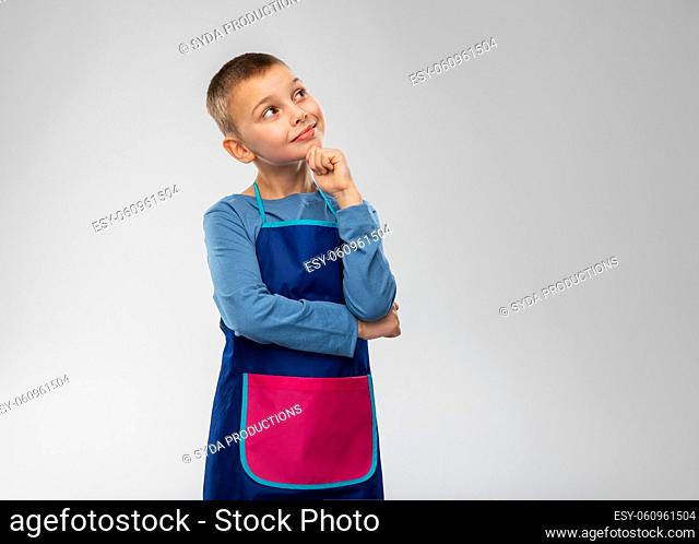smiling little boy in apron thinking