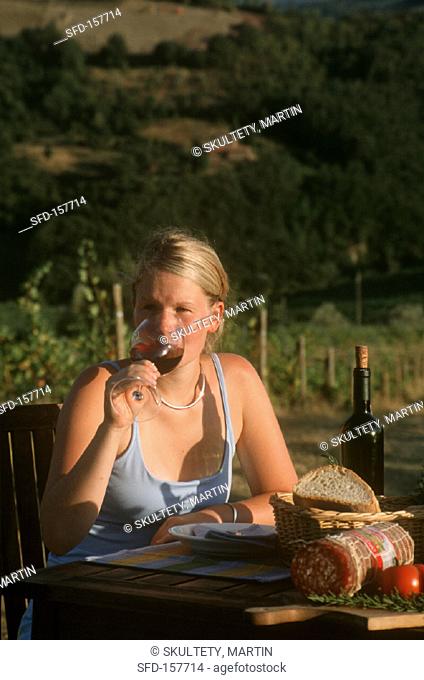 Young woman drinking wine in a Tuscan vineyard
