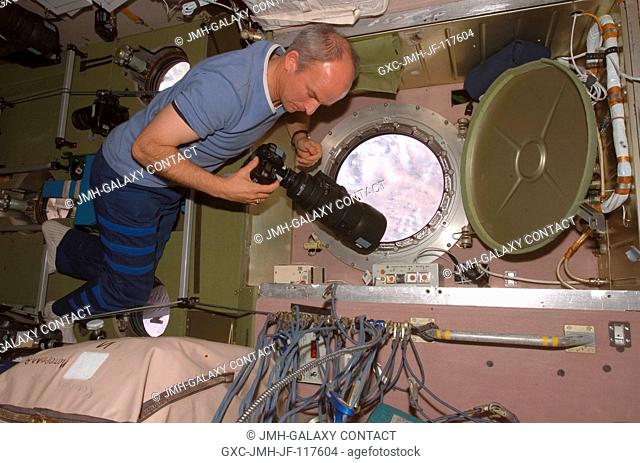 Astronaut Jeffrey N. Williams, Expedition 13 NASA space station science officer and flight engineer, prepares to use a camera to photograph the topography of a...